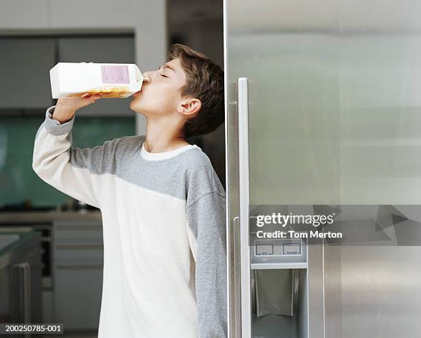 boy (10-12) by fridge, drinking milk from carton, side view - carton milk stock pictures, royalty-free photos & images