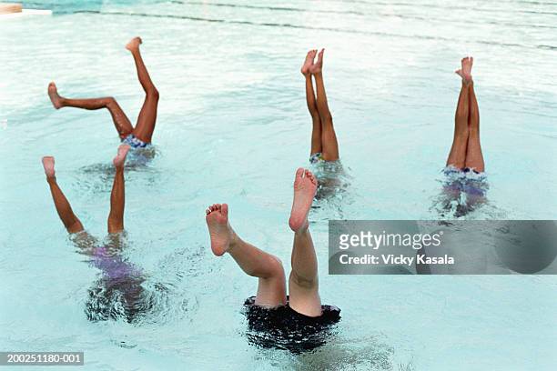 Five children (7-12) doing handstands in swimming pool