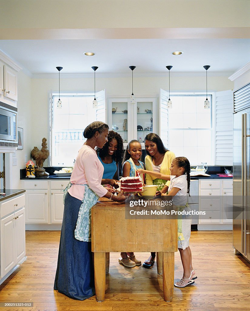 Multi-generational women deocrating cake in kitchen, side view