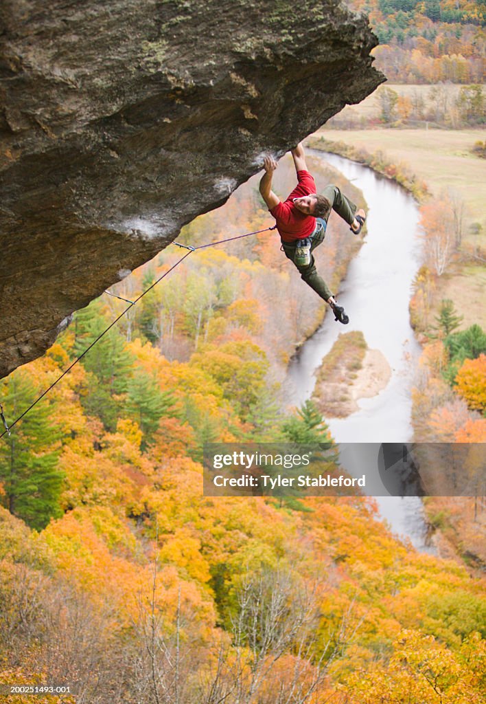 Male rock climber dangling from overhang, elevated view