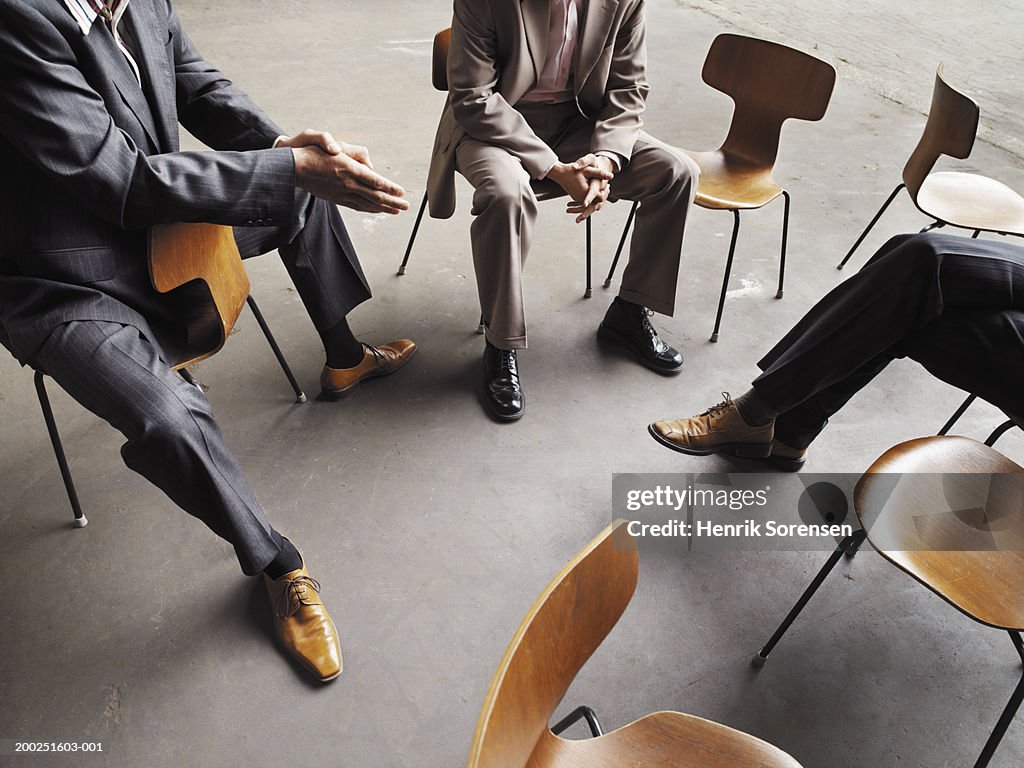 Three men sitting together by empty chairs