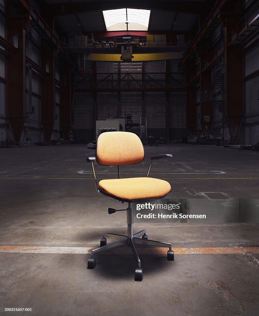 Office chair under spotlight in empty warehouse