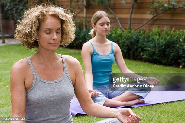 mother and daughter (13-15) meditating in garden, eyes closed - teenager yoga stock pictures, royalty-free photos & images