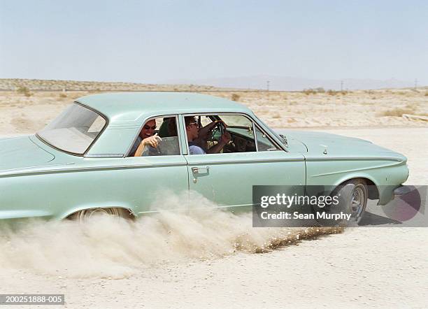 young men riding in car on dirt road - sedan stock pictures, royalty-free photos & images