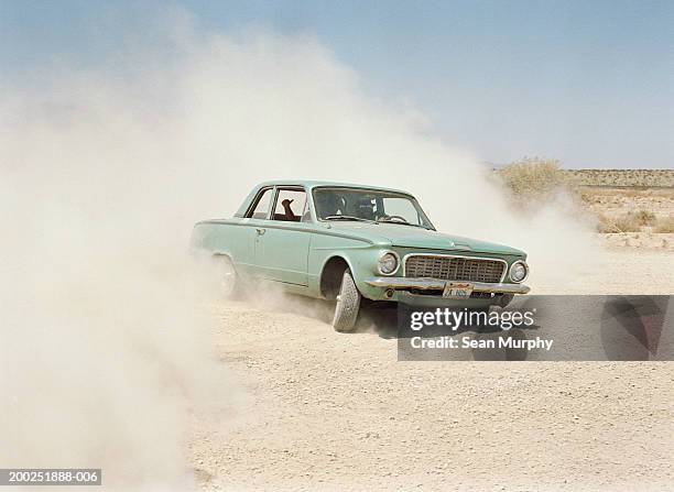 young men riding in car on dirt road, dust cloud - carro tipo sallon imagens e fotografias de stock