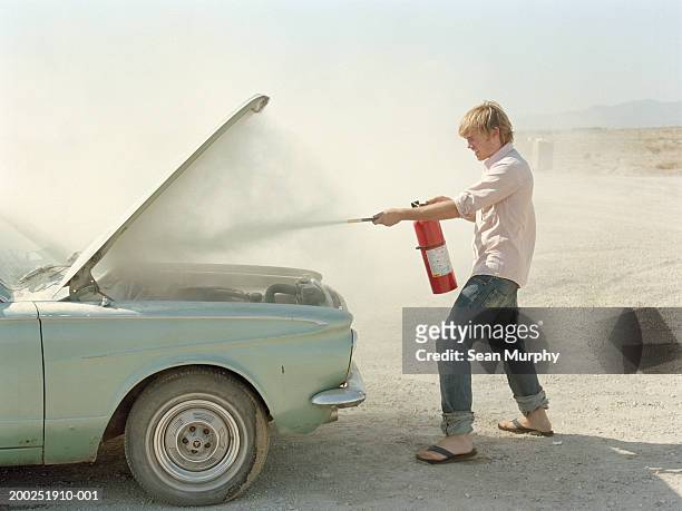 young man spraying fire extinguisher in car hood - dangers of smoking stock pictures, royalty-free photos & images