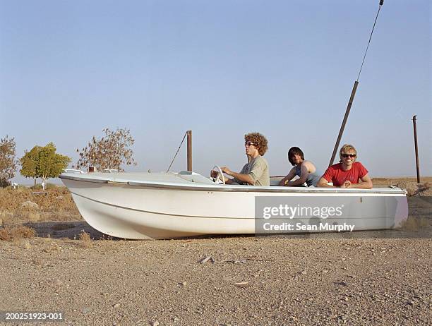 young men riding in boat docked on land - out of context foto e immagini stock