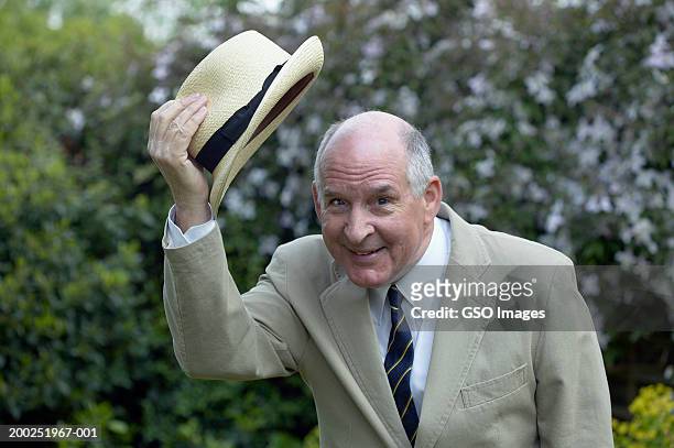 senior man raising hat above head, smiling, portrait - etiquette stock-fotos und bilder