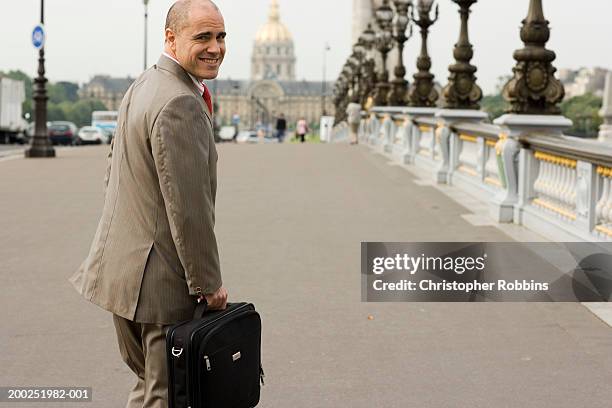 france, paris, pont alexandre iii, man carrying briefcase, smiling - man looking back stock pictures, royalty-free photos & images