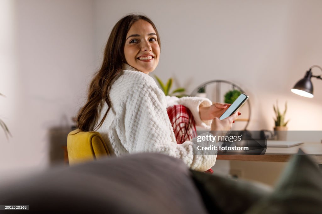 Sitting at her desk in pajamas, still sleepy, texting friends