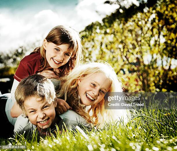 three children (8-12) lying together on grass, laughing, portrait - happy tween girls lying on grass stock pictures, royalty-free photos & images