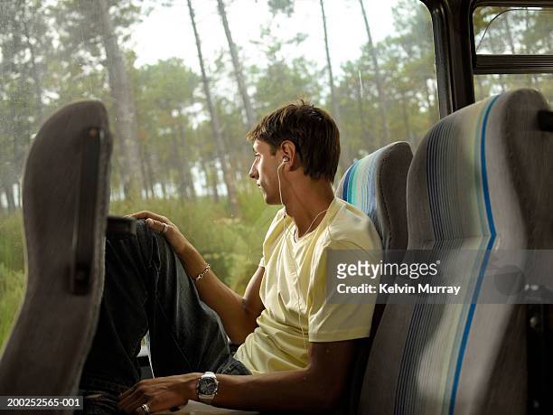 young man sitting on coach wearing earphones facing window - bus side view stock pictures, royalty-free photos & images