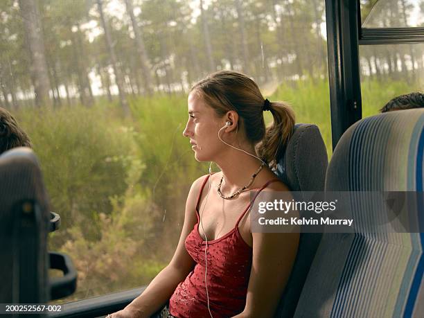 young woman sitting on coach wearing earphones - car top view photos et images de collection