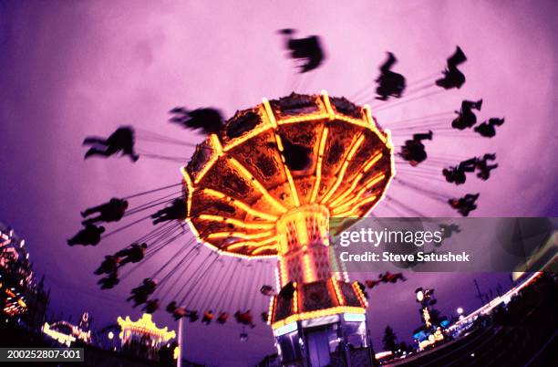 spinning carousel ride at county fair, evening, low angle view - karusell stock-fotos und bilder