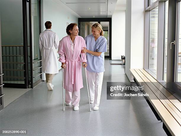 young female nurse assisting female patient on crutches in hospital - crutch bildbanksfoton och bilder