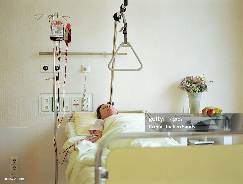 Woman lying in hospital bed with IV drip filled with blood