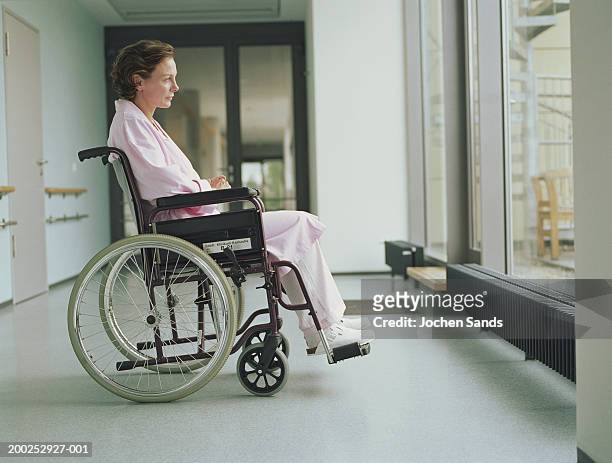 woman in wheelchair in hospital corridor, side view - woman wheelchair stock pictures, royalty-free photos & images