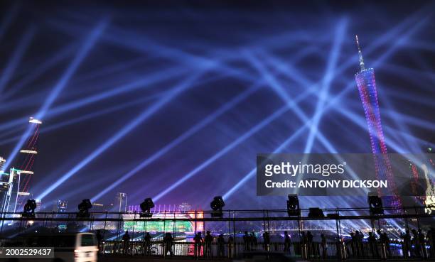 People and vehicles cross a bridge overlooking the opening ceremony area for the upcoming 16th Asian Games, in Guangzhou on November 10, 2010. After...