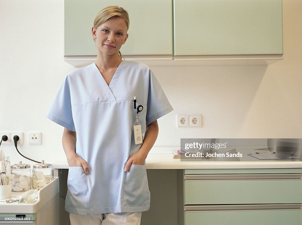 Young female nurse in kitchen, smiling, portrait