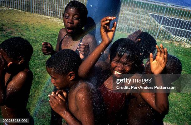 Unidentified children showers in a swimming pool on a hot day on October 19, 2003 in Khayelitsha, the biggest black township outside Cape Town, South...