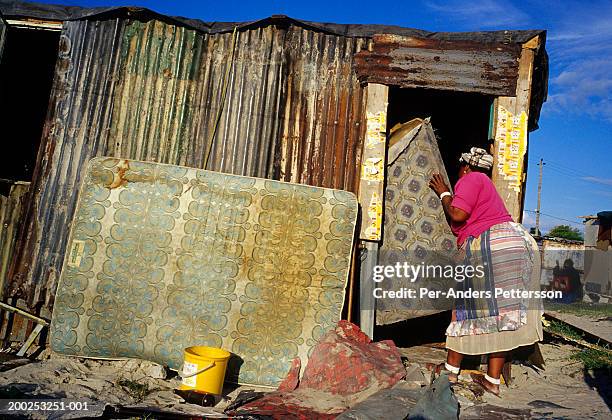 Victoria Mbandazayo, an unemployed woman, carries a mattress inside her newly built shack on October 11, 2003 in Khayelitsha, the biggest black...