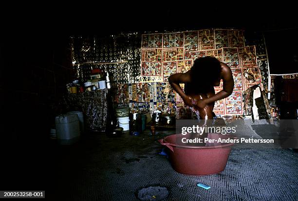 a young girl washes herself in a bucket in her family house in khayelitsha, south africa - 15 years girl bare stock pictures, royalty-free photos & images