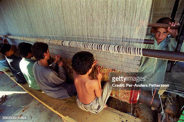 Children works as weavers of Afghan carpets in an illegal factory on October 1, 2001 in Attock, Pakistan. This village has about 20 carpet factories,...