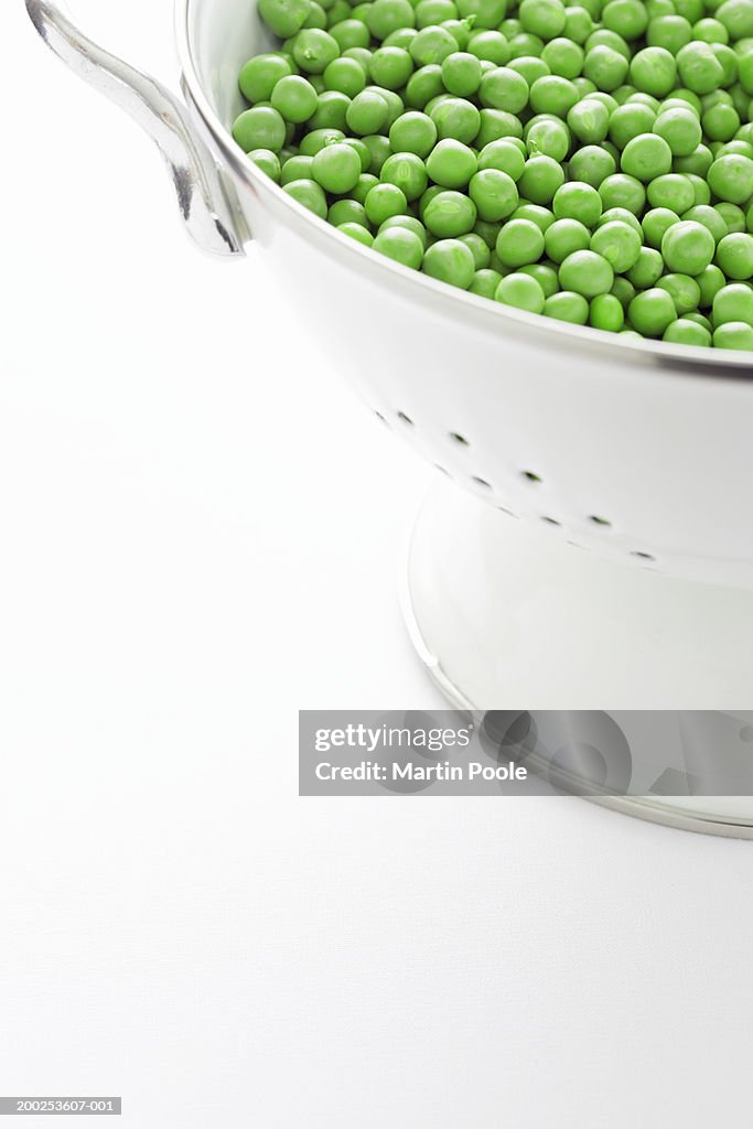 Metal strainer filled with peas, close-up