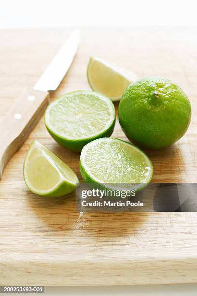 cut limes and knife on wooden board, close-up - lime stock pictures, royalty-free photos & images