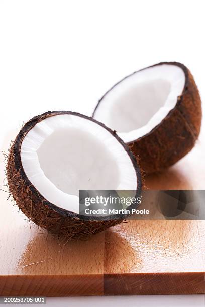 split coconut on wooden board, close-up - kokosnuss stock-fotos und bilder