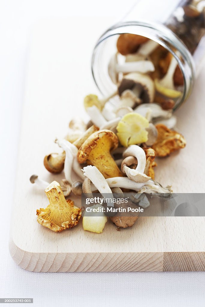 Wild mushrooms in jar and on wooden board, close-up