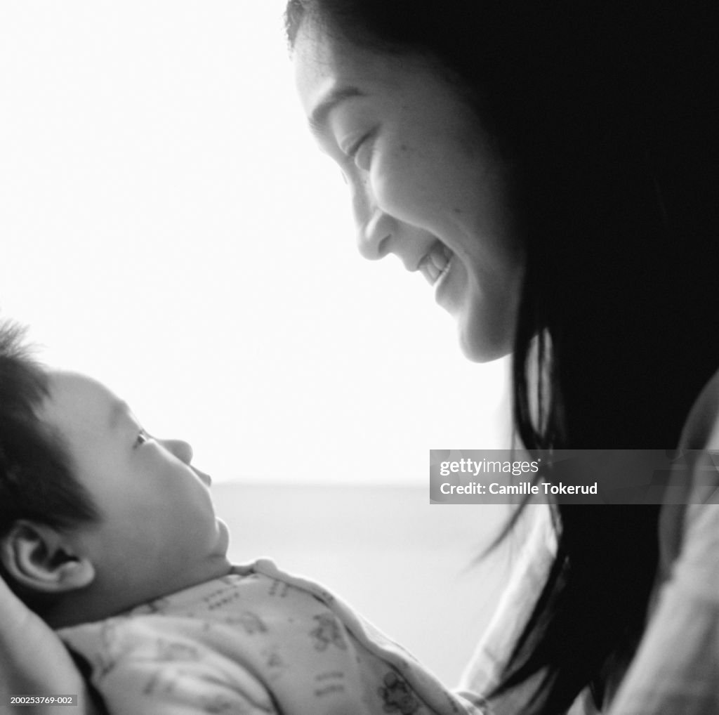 Mother smiling at baby girl (3-6 months), side view (B&W)