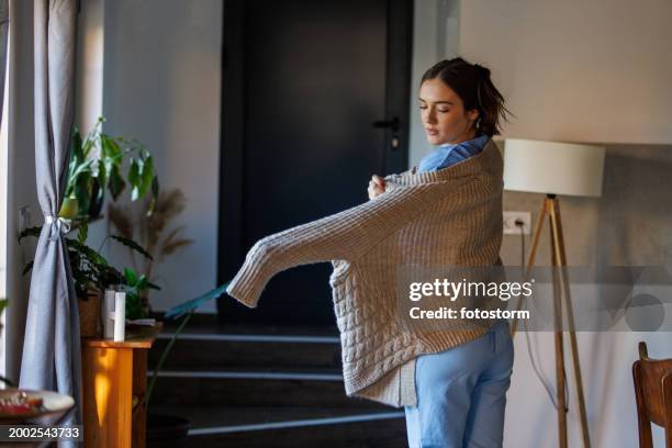 nurse putting on a cardigan, getting ready to leave for work - aankleden stockfoto's en -beelden