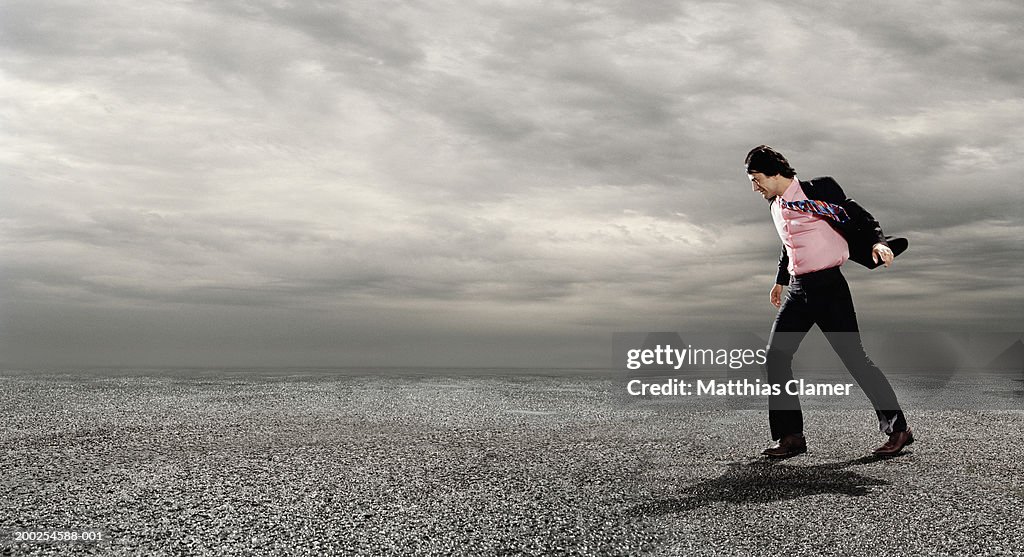 Businessman walking against wind, outdoors, side view