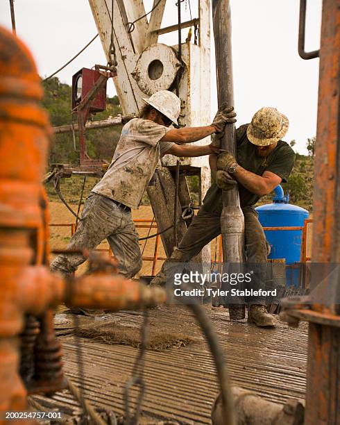 workman on oil rig moving section of drill - oliewerker stockfoto's en -beelden