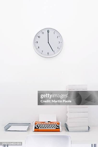 clock on wall above typewriter and 'in and 'out' trays - inbox filing tray stock-fotos und bilder