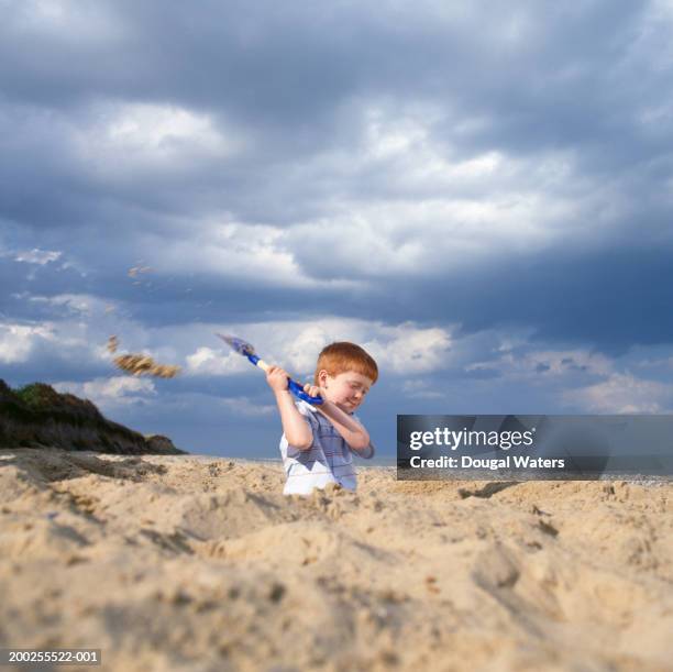 boy (4-6) digging sand pit on beach, smiling, ground view - digging stock pictures, royalty-free photos & images
