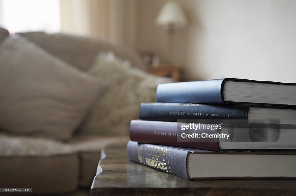 Pile of books on table in living room (focus on books and table)