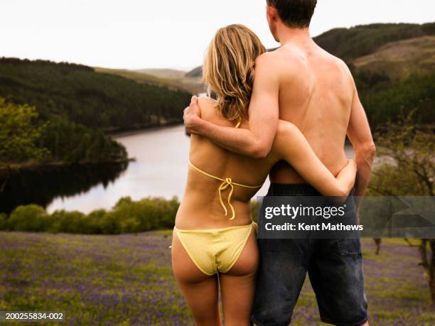 couple embracing in field by lake, wearing swimwear, rear view - llyn brianne reservoir stock pictures, royalty-free photos & images