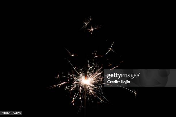 burning sparkler against sky - chispas fotografías e imágenes de stock
