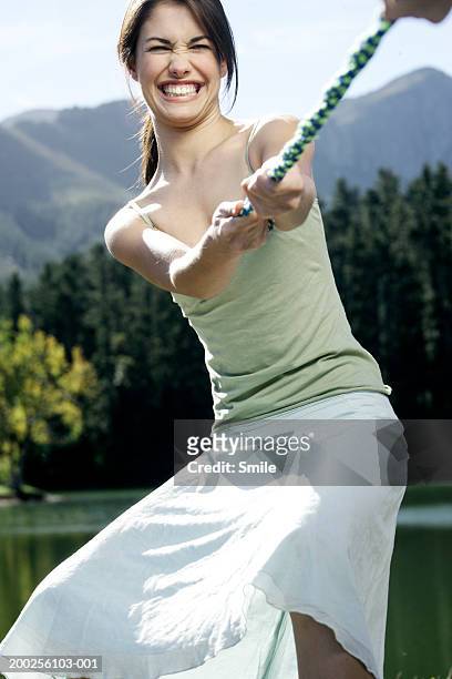 young woman playing tug-of-war - tug of war stock pictures, royalty-free photos & images