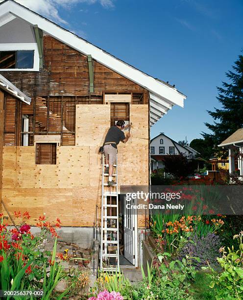 man on ladder against house under construction, rear view - seattle home stock pictures, royalty-free photos & images