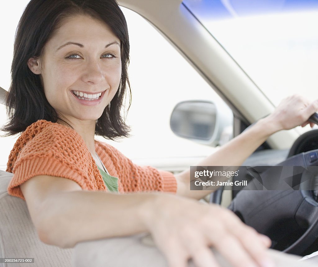 Young woman in driver's seat smiling, portrait