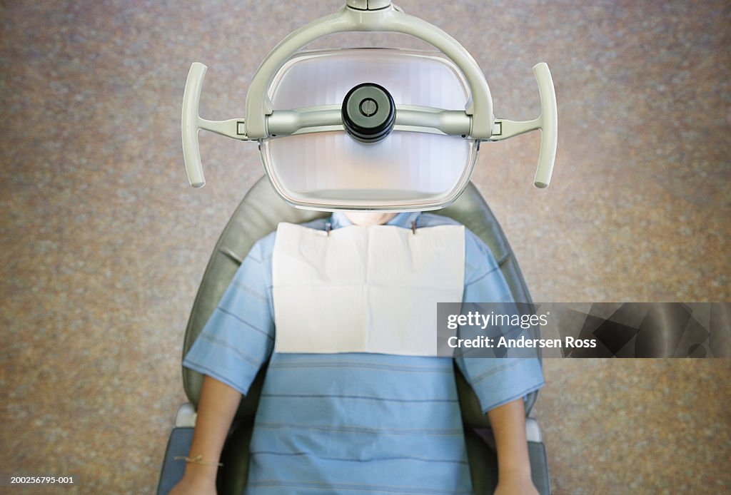 Boy (10-12) lying on dentist's chair, overhead view