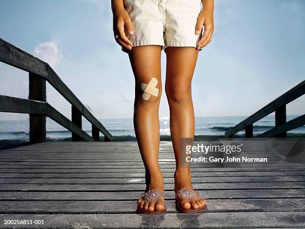 girl (6-8) with bandage on knee standing on boardwalk, low section - human knee stock pictures, royalty-free photos & images