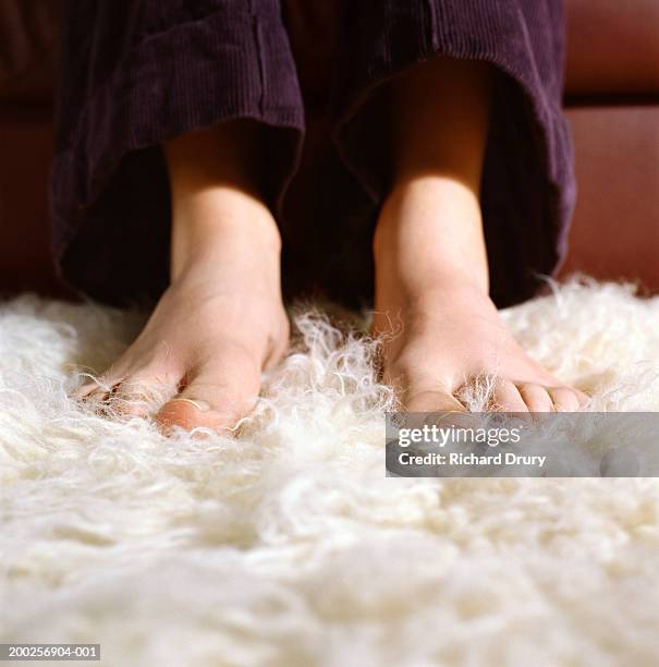 young woman with bare feet on furry carpet, low section, close-up - womans bare feet fotografías e imágenes de stock