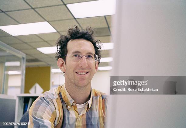 businessman sitting in front of computer monitor, smiling - geek stockfoto's en -beelden