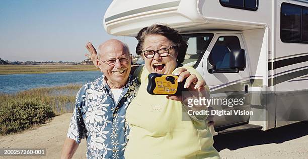senior couple taking photo of themselves by camper van - mobiles haus stock-fotos und bilder