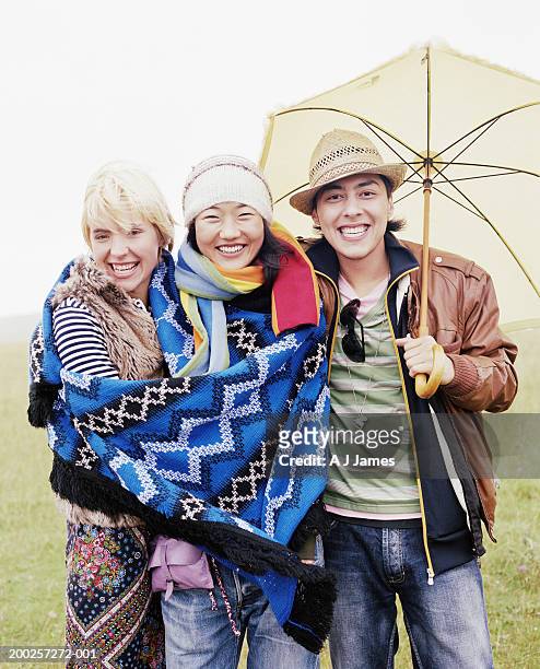 three friends embracing under umbrella, smiling, portrait - native korean stock pictures, royalty-free photos & images