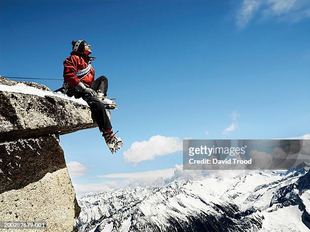 male mountain climber sitting on overhanging rock, low angle view - on top of stock pictures, royalty-free photos & images